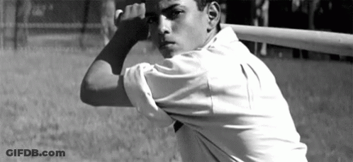 A Man In A White Shirt Is Holding A Baseball Bat Over His Head GIF