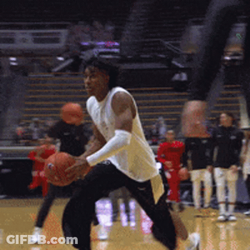 A Man In A White Shirt Is Holding A Basketball On A Court GIF