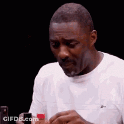 A Man In A White Shirt Is Holding A Bottle Of Hot Sauce In His Hand . GIF