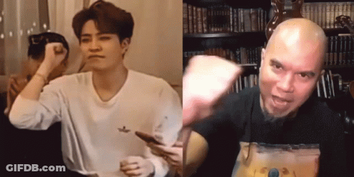 A Man In A White Shirt Is Holding A Cell Phone Next To A Man In A Black Shirt GIF