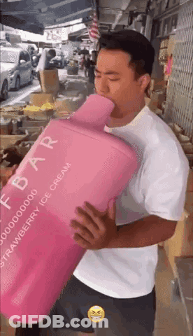 A Man In A White Shirt Is Holding A Large Pink Bottle Of Strawberry Ice Cream GIF
