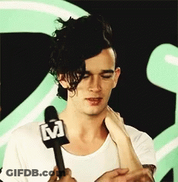 A Man In A White Shirt Is Holding A Microphone GIF