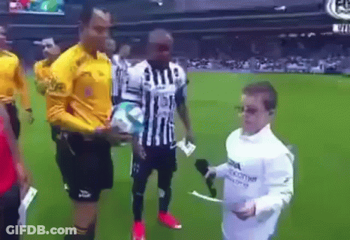 A Man In A White Shirt Is Holding A Microphone And Talking To A Soccer Player On A Field . GIF