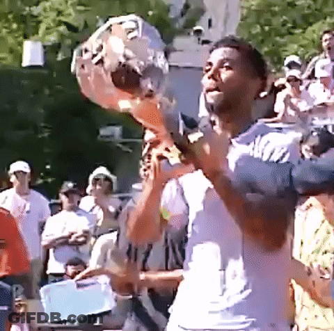 A Man In A White Shirt Is Holding A Microphone In Front Of A Crowd GIF