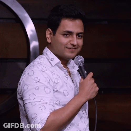 A Man In A White Shirt Is Holding A Microphone With A C On It GIF