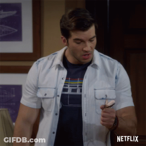 A Man In A White Shirt Is Holding A Pair Of Glasses And A Netflix Logo Is Behind Him GIF