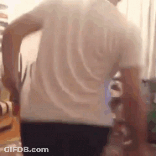 A Man In A White Shirt Is Holding A Pair Of Scissors In His Hand . GIF
