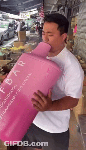 A Man In A White Shirt Is Holding A Pink Container That Says Strawberry Ice Cream GIF