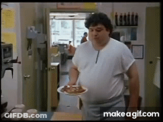 A Man In A White Shirt Is Holding A Plate Of Food In His Hand . GIF