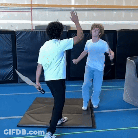 A Man In A White Shirt Is Holding A Sword GIF