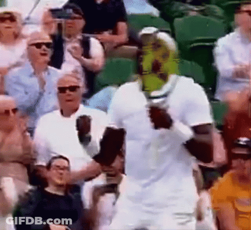 A Man In A White Shirt Is Holding A Tennis Racket In Front Of A Crowd Of People . GIF