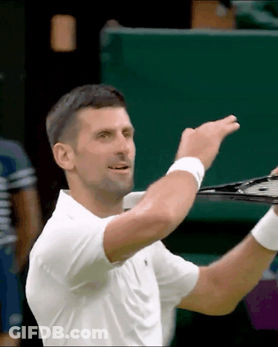 A Man In A White Shirt Is Holding A Tennis Racket In His Hand GIF