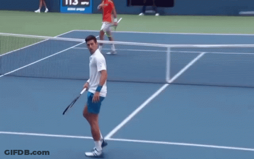A Man In A White Shirt Is Holding A Tennis Racquet GIF