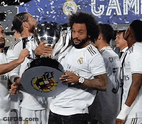 A Man In A White Shirt Is Holding A Trophy In Front Of A Group Of Soccer Players . GIF