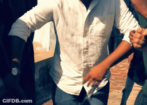 A Man In A White Shirt Is Holding Another Man 'S Hand GIF