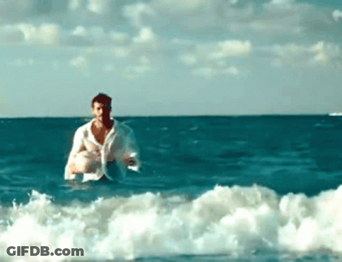 A Man In A White Shirt Is In The Ocean GIF