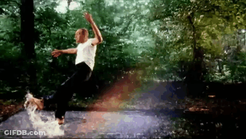 A Man In A White Shirt Is Jumping In A Puddle Of Water GIF