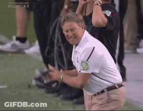 A Man In A White Shirt Is Kneeling Down On A Field . GIF