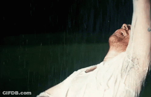 A Man In A White Shirt Is Laughing In The Rain GIF