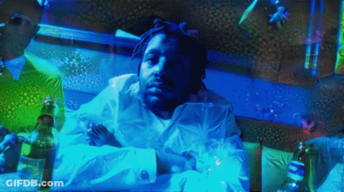 A Man In A White Shirt Is Laying On A Bed With A Bottle Of Beer GIF