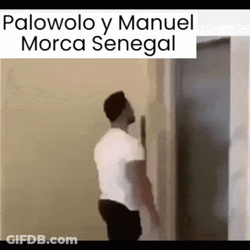 A Man In A White Shirt Is Leaning Against A Wall With The Words Palovolo Y Manuel Morca Senegal Above Him GIF