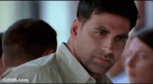 A Man In A White Shirt Is Looking At A Woman In A Crowd . GIF