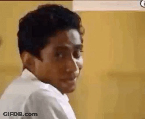 A Man In A White Shirt Is Making A Funny Face And Looking At The Camera . GIF