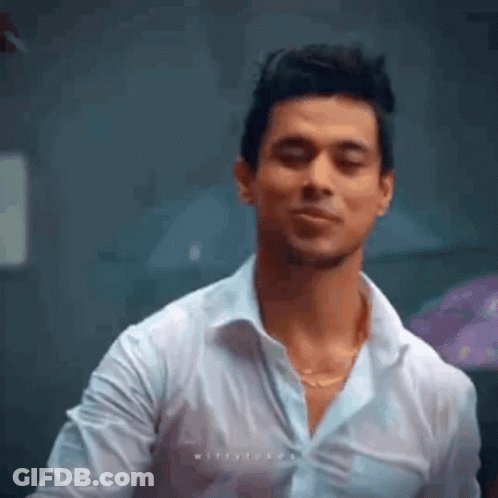 A Man In A White Shirt Is Making A Funny Face While Standing In A Room . GIF