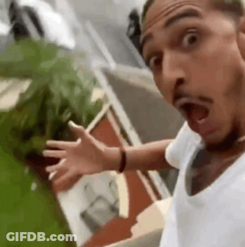 A Man In A White Shirt Is Making A Funny Face With His Mouth Open And His Arms Outstretched . GIF