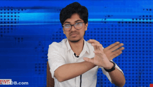 A Man In A White Shirt Is Making A Gesture With His Hands In Front Of A News Background GIF