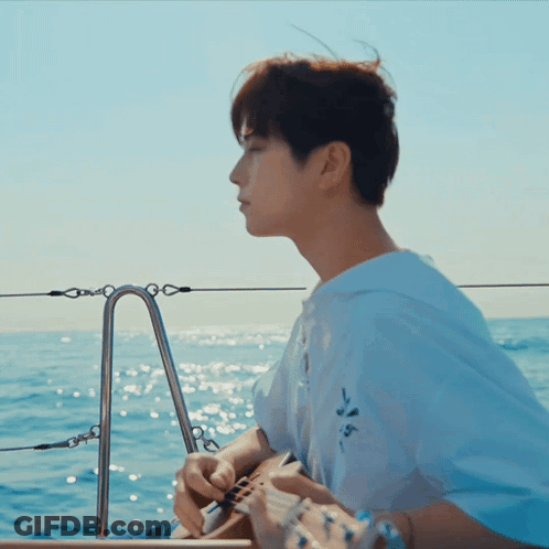 A Man In A White Shirt Is Playing A Guitar In The Ocean GIF