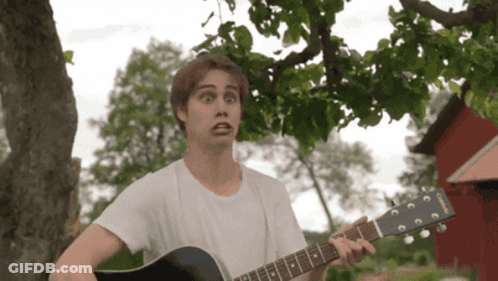 A Man In A White Shirt Is Playing A Guitar With A Yamaha Logo On It GIF
