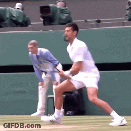 A Man In A White Shirt Is Playing Tennis On A Tennis Court GIF