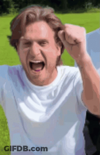 A Man In A White Shirt Is Raising His Fist In The Air . GIF