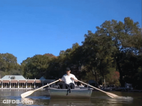 A Man In A White Shirt Is Rowing A Boat In A Lake GIF