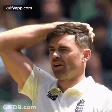 A Man In A White Shirt Is Scratching His Head With His Hands . GIF