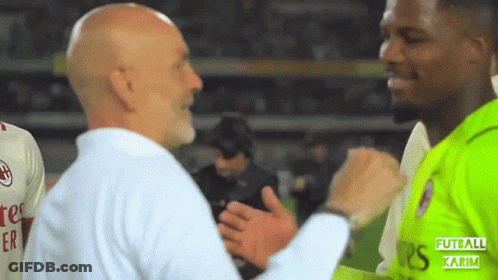 A Man In A White Shirt Is Shaking Hands With A Man In A Green Shirt With The Word Futball Karim On It GIF