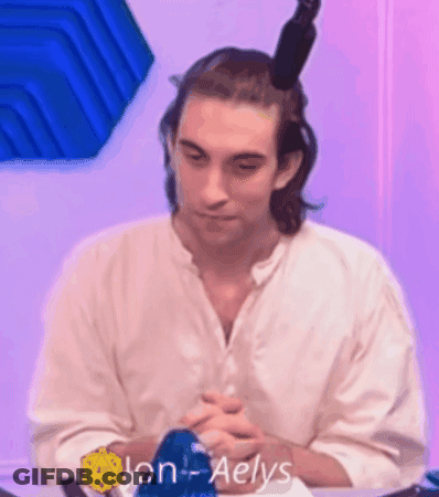 A Man In A White Shirt Is Sitting At A Table With His Hands Folded . GIF