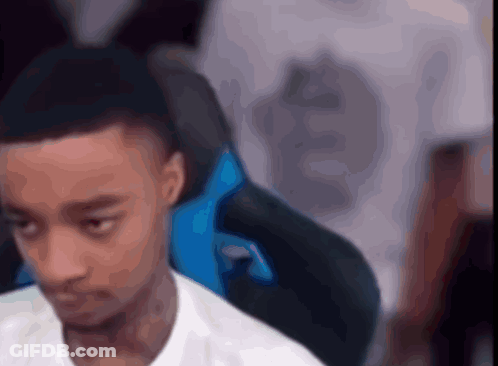 A Man In A White Shirt Is Sitting In A Blue Chair With His Eyes Closed GIF