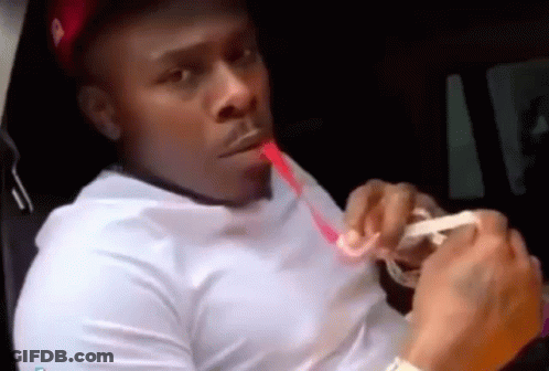 A Man In A White Shirt Is Sitting In A Car Drinking From A Straw . GIF