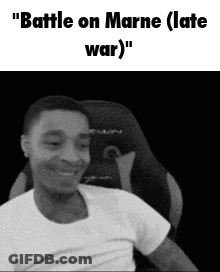 A Man In A White Shirt Is Sitting In A Chair And Smiling . GIF