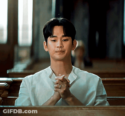 A Man In A White Shirt Is Sitting In A Church With His Hands Folded GIF