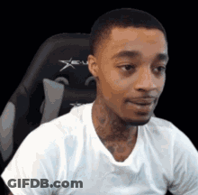 A Man In A White Shirt Is Sitting In A Gaming Chair And Making A Funny Face . GIF