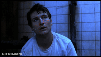 Man In White Shirt Sitting In Front Of Blue Tiles GIF
