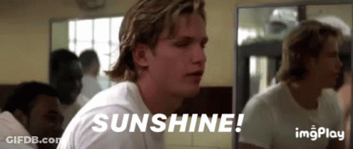 A Man In A White Shirt Is Sitting In Front Of A Mirror With The Words Sunshine Written On It . GIF