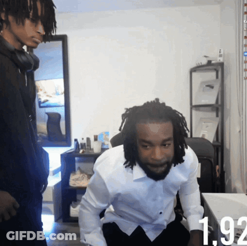 A Man In A White Shirt Is Sitting In Front Of A Table With The Number 192 Visible GIF