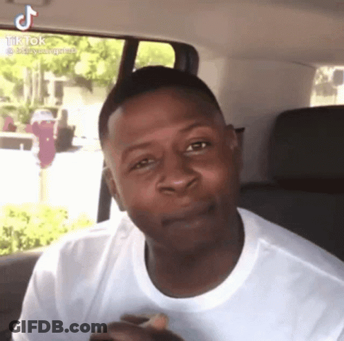 A Man In A White Shirt Is Sitting In The Back Seat Of A Car And Making A Face . GIF