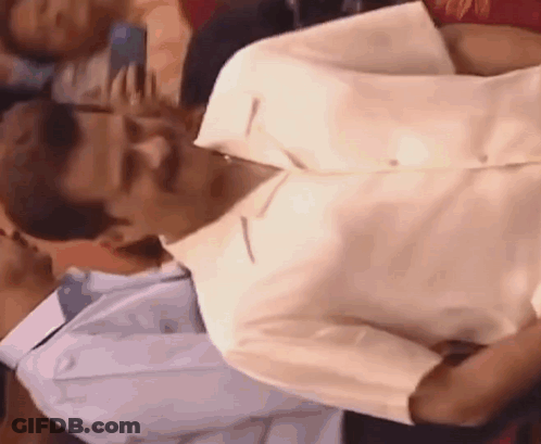 A Man In A White Shirt Is Sitting Next To Another Man In A Blue Shirt . GIF