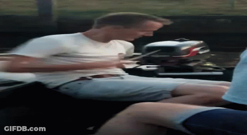 A Man In A White Shirt Is Sitting On A Boat Next To A Boat Motor . GIF