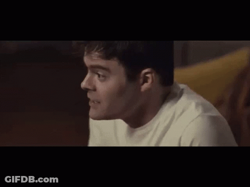 A Man In A White Shirt Is Sitting On A Couch And Looking At Something . GIF